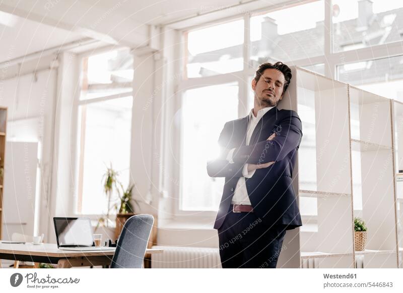 Businessman leaning against shelf in office Exhaustion Weary exhausted Business man Businessmen Business men males standing Office Offices business people