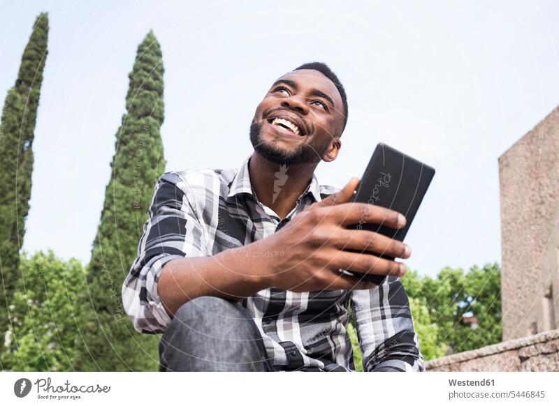 Portrait of happy young man with cell phone men males Smartphone iPhone Smartphones portrait portraits Adults grown-ups grownups adult people persons