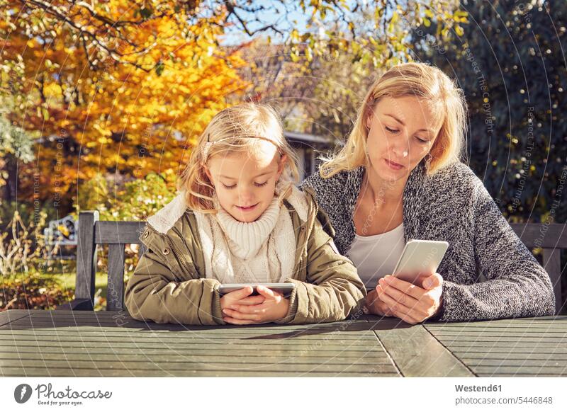 Mother with daughter at garden table using cell phones mother mommy mothers ma mummy mama daughters mobile phone mobiles mobile phones Cellphone parents family