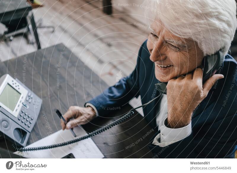 Smiling senior businessman on the phone in his office Businessman Business man Businessmen Business men offices office room office rooms call telephoning