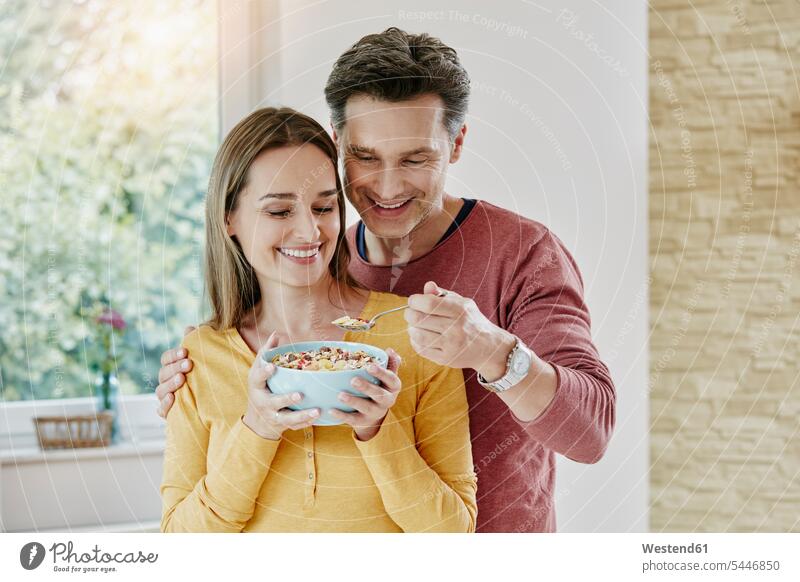 Happy couple sharing muesli at home happiness happy portrait portraits eating twosomes partnership couples Granola Muesli cereals smiling smile holding people