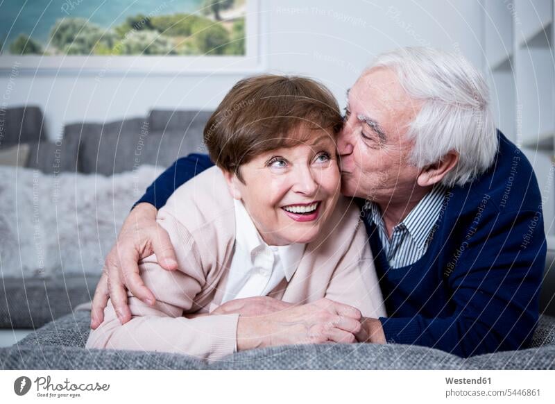 Senior couple lying on couch, hugging and kissing settee sofa sofas couches settees kisses embracing embrace Embracement twosomes partnership couples