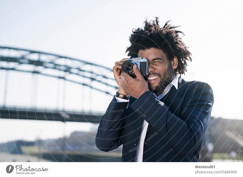 Smiling man in suit at the riverside taking a picture with a vintage camera photographing cameras men males smiling smile Adults grown-ups grownups adult people