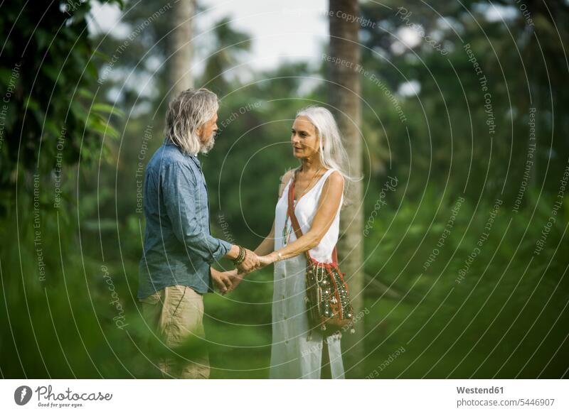 Affectionate senior couple holding hands in tropical landscape with palm trees nature natural world on the move on the way on the go on the road elder couples