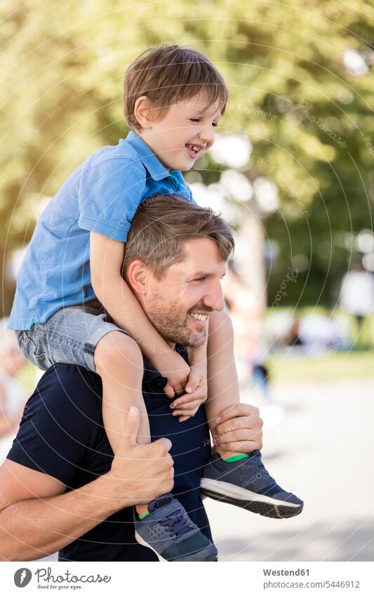 Father carrying son on shoulders sons manchild manchildren father pa fathers daddy dads papa family families park parks happiness happy smiling smile people