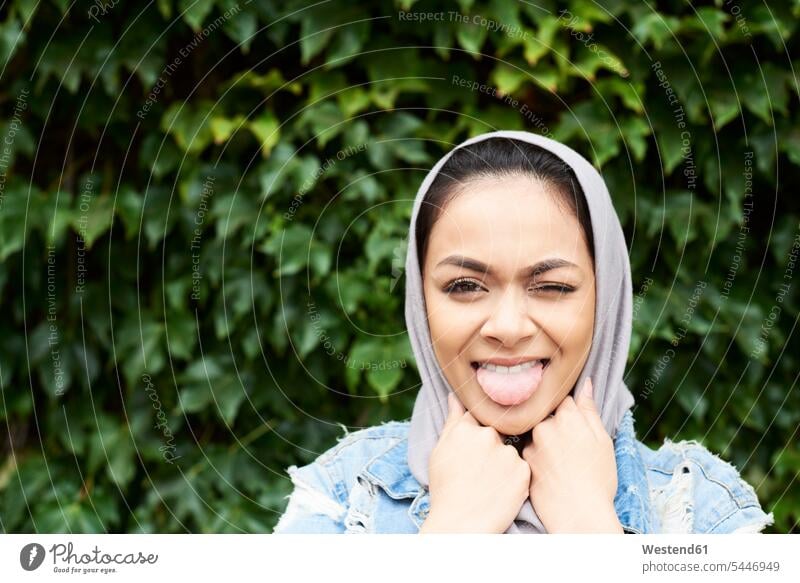 Portrait of young woman wearing hijab stciking her tongue out headscarf head scarf head scarves Head Scarf head cloths headscarves Muslim tongues portrait