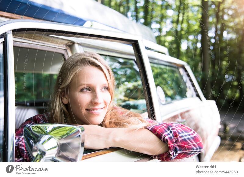 Smiling young woman in car in forest females women automobile Auto cars motorcars Automobiles woods forests smiling smile Adults grown-ups grownups adult people