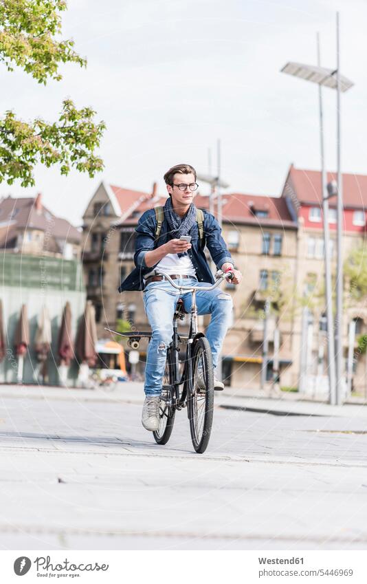Young man with bicycle in the city holding cell phone men males riding mobile phone mobiles mobile phones Cellphone cell phones bikes bicycles Adults grown-ups