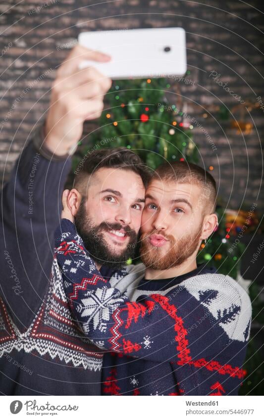 Portrait of happy gay couple taking selfie with smartphone at Christmas time at home portrait portraits Selfie Selfies Gay Couple Gays same-sex couple