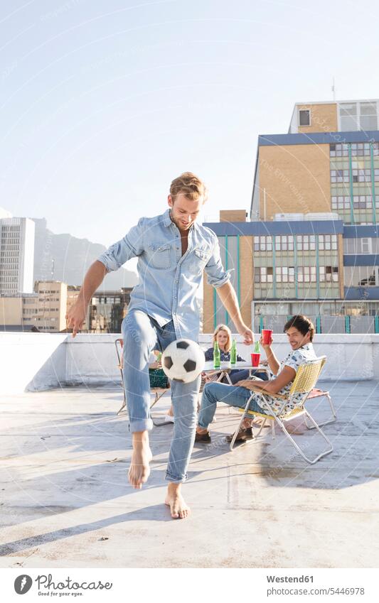 Friends meeting on rooftop terrace in summer, playing football cozy sociable comfortable cosy casual leisure wear casual clothing casual wear casual clothes