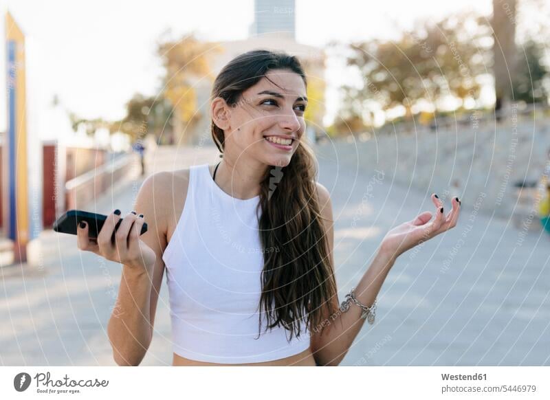 Portrait of grinning young woman with cell phone females women Smartphone iPhone Smartphones portrait portraits Adults grown-ups grownups adult people persons