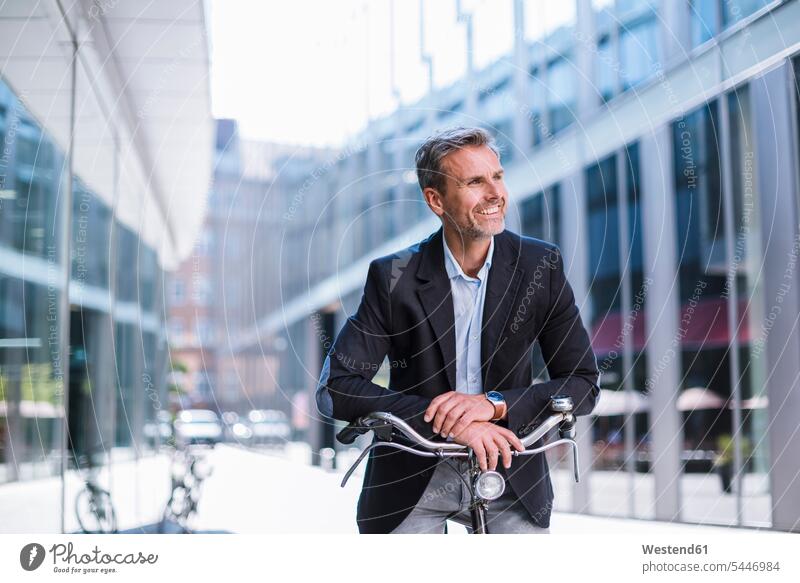 Smiling businessman on bicycle in the city bikes bicycles smiling smile Businessman Business man Businessmen Business men town cities towns transportation