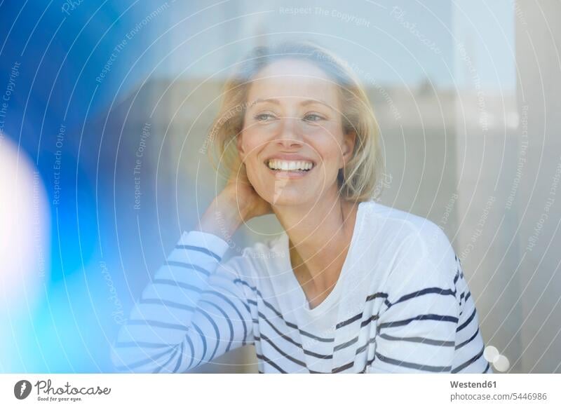 Portrait of laughing blond woman behind window pane portrait portraits females women Adults grown-ups grownups adult people persons human being humans