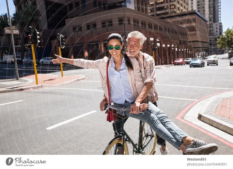 Mature couple meeting in the city town cities towns bicycle bikes bicycles twosomes partnership couples together on the move on the way on the go on the road