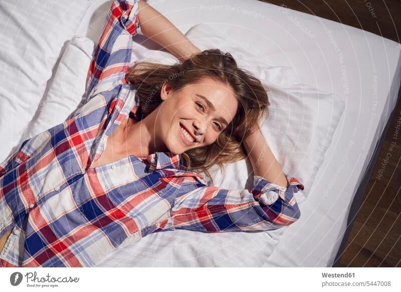 Portrait of laughing woman lying on bed with hands behind her head beds females women portrait portraits Adults grown-ups grownups adult people persons