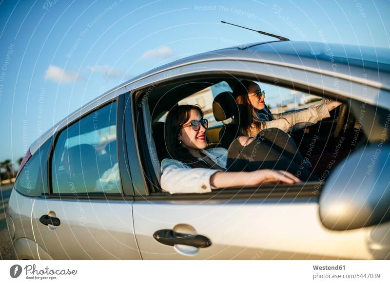 Two young women traveling in a car female friends automobile Auto cars motorcars Automobiles mate friendship motor vehicle road vehicle road vehicles