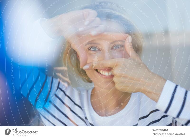 Portrait of laughing blond woman building frame with her fingers while looking at viewer portrait portraits females women Adults grown-ups grownups adult people