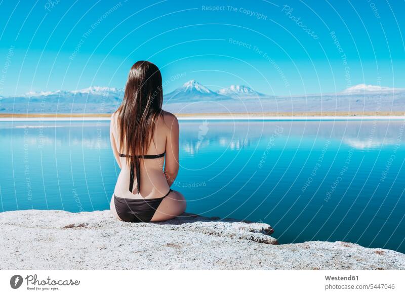 Chile, Atacama Desert, back view of woman sitting on edge of Laguna Cejar females women Adults grown-ups grownups adult people persons human being humans