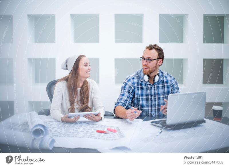 Young man and woman discussing project in design office discussion designer designers design professional design professionals Design Occupation together Office