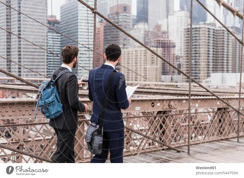 USA, New York City, two businessmen on Brooklyn Bridge talking speaking bridge bridges New York State Businessman Business man Businessmen Business men