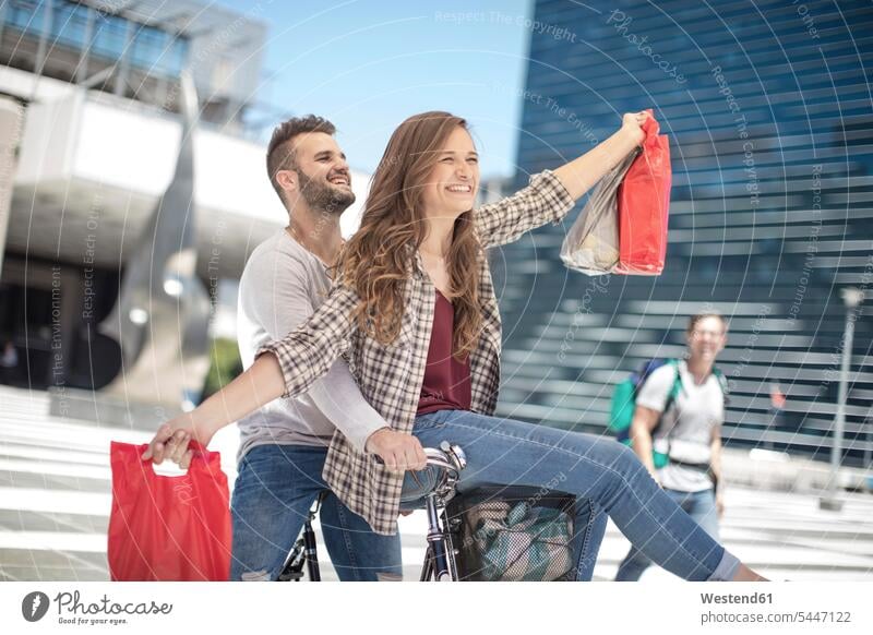 Happy young couple having fun in the city riding bicycle with shopping bags shopping-bag shopping-bags Fun funny bikes bicycles twosomes partnership couples