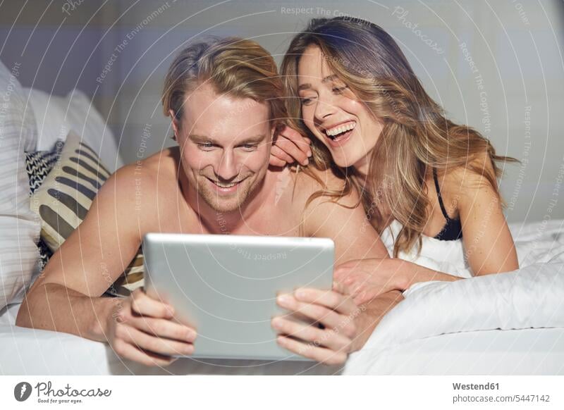 Portrait of relaxed couple with tablet lying on bed portrait portraits digitizer Tablet Computer Tablet PC Tablet Computers iPad Digital Tablet digital tablets