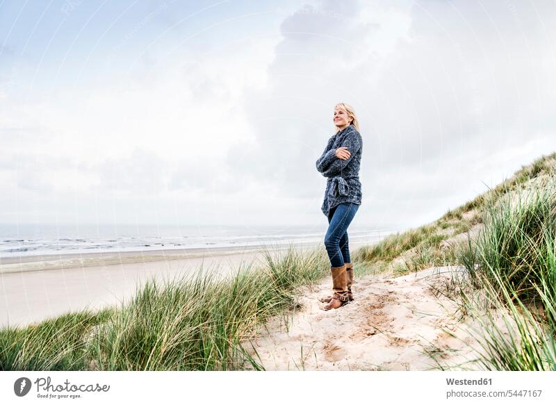 Smiling woman standing in dunes sand dune sand dunes smiling smile females women beach beaches Adults grown-ups grownups adult people persons human being humans