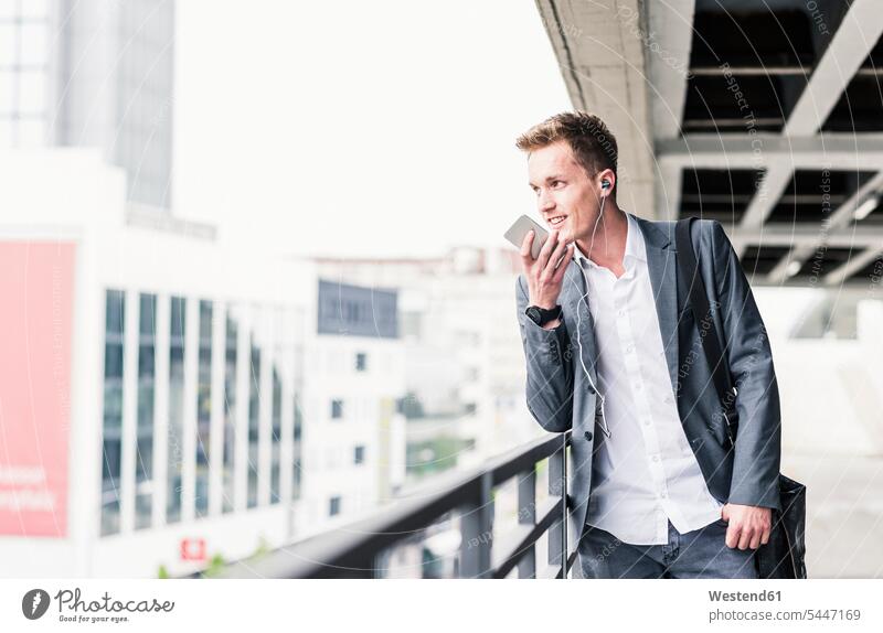 Young businessman using smartphone, standing on parking level urban urbanity on the move on the way on the go on the road Smartphone iPhone Smartphones call
