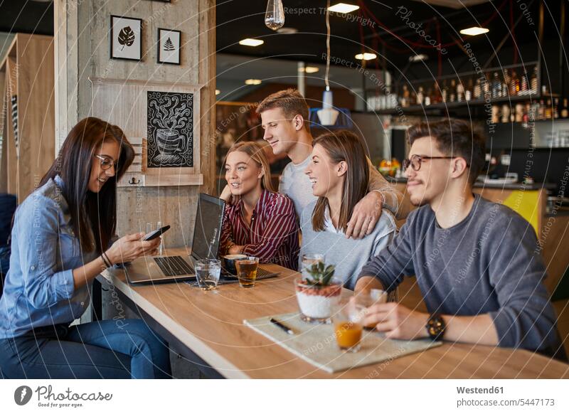 Group of friends sitting together in a cafe with laptop, smartphone and drinks happiness happy Smartphone iPhone Smartphones Seated Laptop Computers laptops