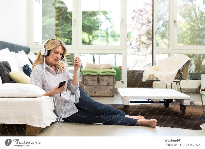Relaxed woman at home listening to music females women headphones headset relaxed relaxation hearing lying laying down lie lying down Adults grown-ups grownups