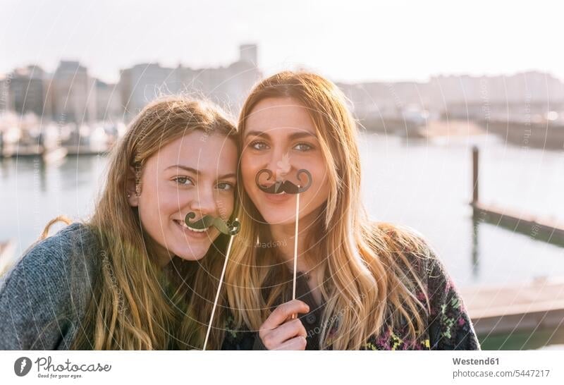 Portrait of two friends with toy moustaches mate female friend portraits smile mustache caucasian appearance caucasian ethnicity european Teen Teenage teenagers