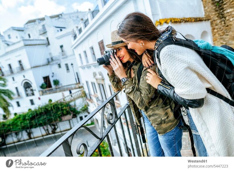 Two young women in a town taking pictures with a camera female friends photographing cameras smiling smile mate friendship female tourist city cities towns