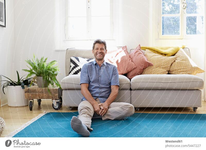 Man sitting at home, looking happy man men males floor floors Seated relaxation relaxed relaxing comfortable Adults grown-ups grownups adult people persons
