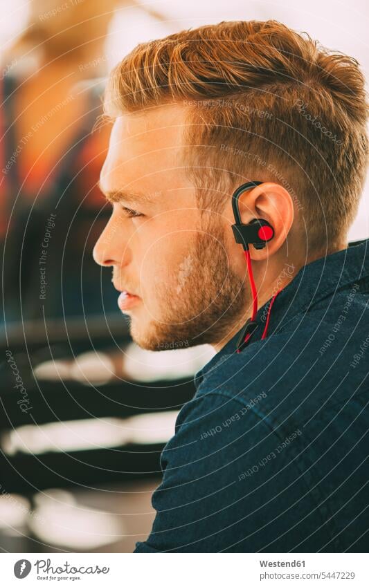 Young man wearing headset outdoors men males headphones earphones ear phone ear phones Adults grown-ups grownups adult people persons human being humans