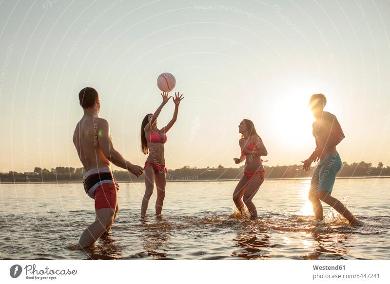 Happy friends playing with a ball in water Fun having fun funny lake lakes friendship waters body of water Volleyball Sun evening in the evening leisure