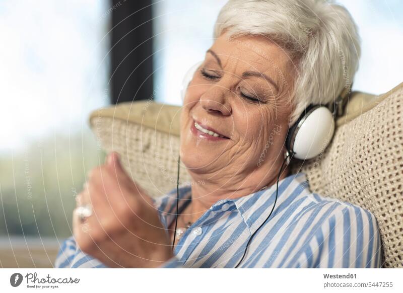 Smiling senior woman wearing headphones listening to music at home headset senior women elder women elder woman old females smiling smile hearing senior adults