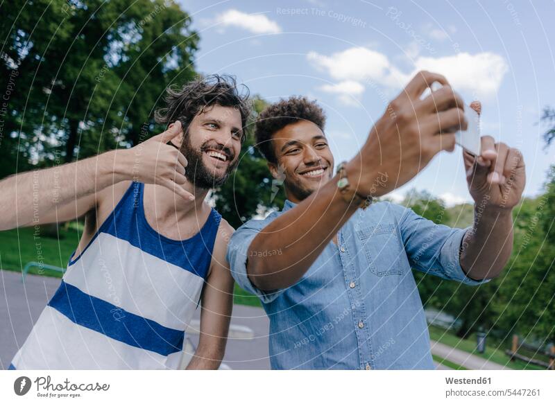 Two happy friends taking a selfie in a skatepark Selfie Selfies man men males Skateboard Park skate park happiness mobile phone mobiles mobile phones Cellphone