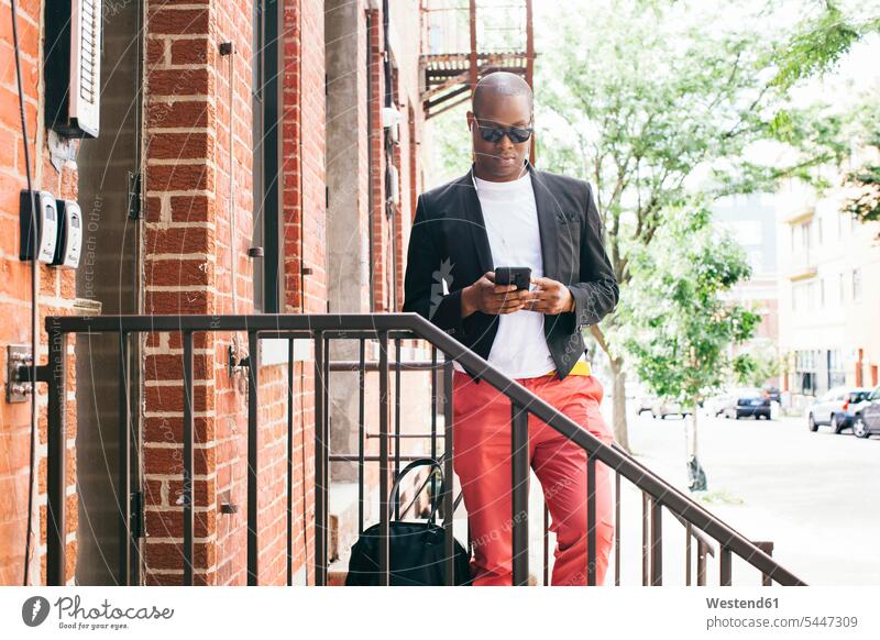 USA, NYC, Brooklyn, Man waiting on stairs, using smartphone man men males Smartphone iPhone Smartphones cool attitude composed coolness laid-back reading hip