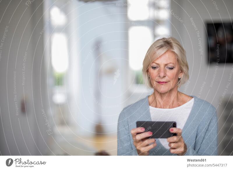 Portrait of senior woman at home looking at cell phone senior women elder women elder woman old Smartphone iPhone Smartphones portrait portraits senior adults