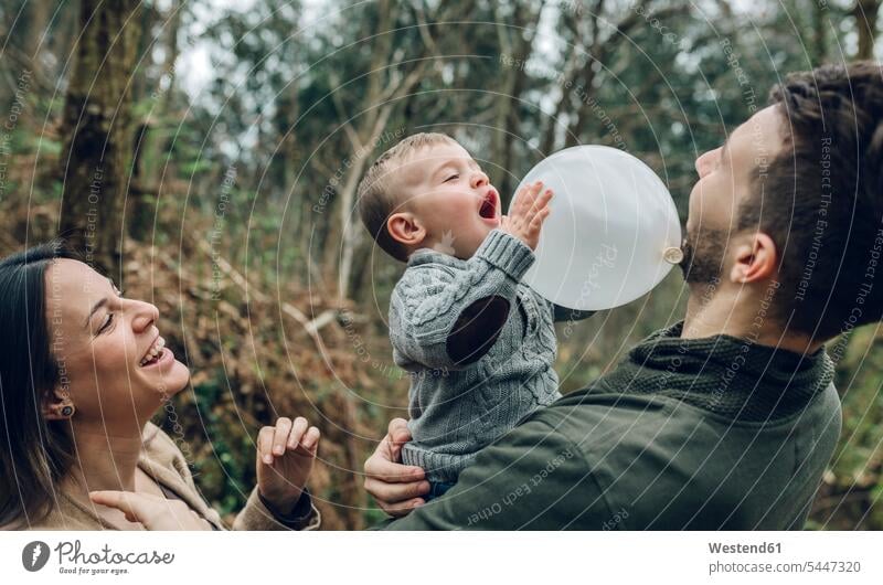 Happy family playing with a balloon in forest families balloons woods forests people persons human being humans human beings playful leisure free time
