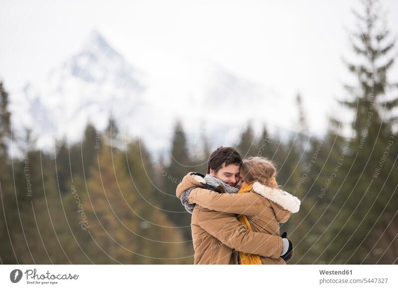 Happy young couple hugging each other in winter landscape twosomes partnership couples hibernal embracing embrace Embracement people persons human being humans