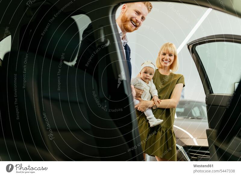 Family in car dealership choosing family vehicle family car families car dealerships Showroom select choose selecting together automobile Auto cars motorcars