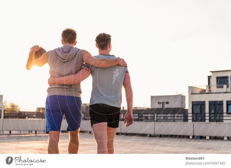 Friends playing basketball at sunset on a rooftop young fit embracing embrace Embracement hug hugging basketballs friends mate Basketball sport sports