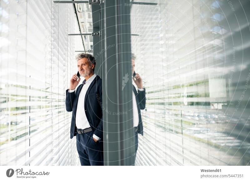 Mature businessman on cell phone at outside sunblind standing Businessman Business man Businessmen Business men mobile phone mobiles mobile phones Cellphone