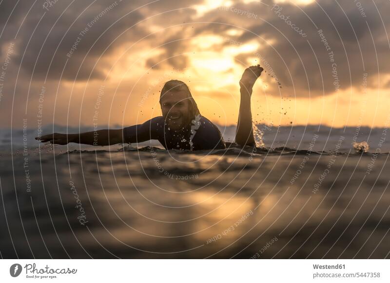 Indonesia, Bali, surfer in the ocean at sunrise surfboard surfboards surfers sun rise sunrises surfing surf ride surf riding Surfboarding water sports