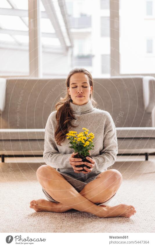 Woman with closed eyes sitting on floor holding flower Seated Flower Flowers woman females women relaxed relaxation Plant Plants Adults grown-ups grownups adult
