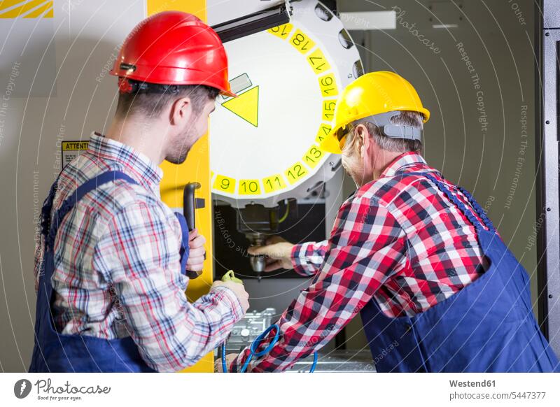 Two men in factory working at CNC machine factories At Work industry industrial operating operate business business world business life occupation profession