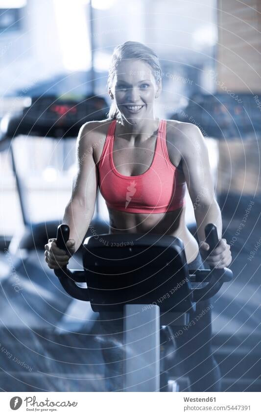 Portrait of smiling woman on spinning bike in gym exercise machine exercise machines stationary bike Stationary Bikes exercising training practising smile