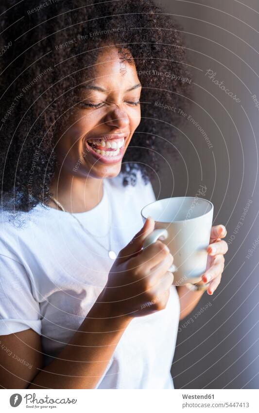 Laughing woman holding cup of coffee Coffee laughing Laughter females women Drink beverages Drinks Beverage food and drink Nutrition Alimentation