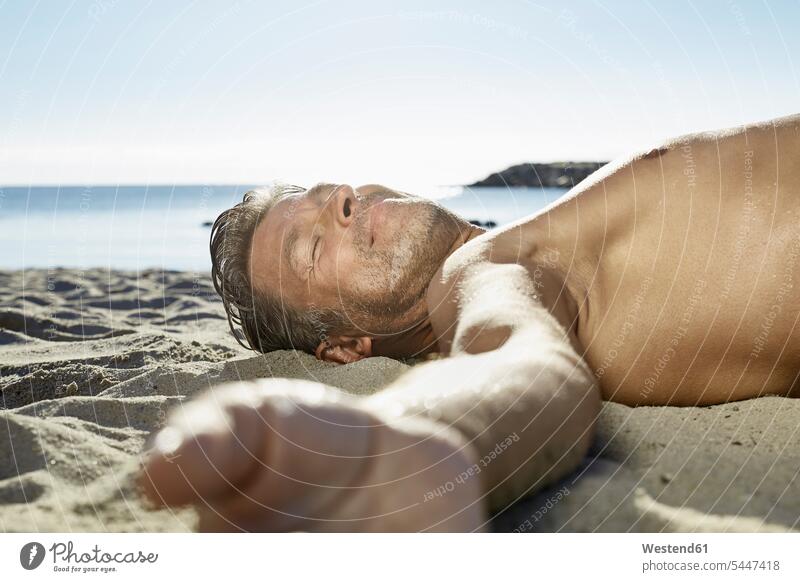 Mature man relaxing on sandy beach beaches men males Adults grown-ups grownups adult people persons human being humans human beings lying laying down lie